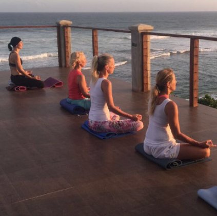 Frauen praktizieren Yoga auf einer Sonnenterrasse mit Blick auf den Indischen Ozean.